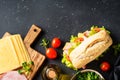 Ciabatta sandwich with lettuce, cheese, tomatoes and ham on black table. Royalty Free Stock Photo