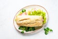 Ciabatta sandwich with lettuce, cheese, tomatoes and ham on white table. Royalty Free Stock Photo