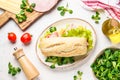 Ciabatta sandwich with lettuce, cheese, tomatoes and ham on white table. Royalty Free Stock Photo