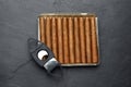 Cigars and guillotine cutter on black table, top view