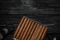 Cigars and guillotine cutters on black wooden table, flat lay. Space for text Royalty Free Stock Photo