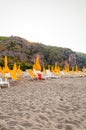 White plastic and metal with yellow fabric deckchairs, yellow umbrellas on the sand beach in Odyssey camping in Italy