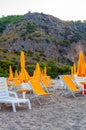 White plastic and metal with yellow fabric deckchairs, yellow umbrellas on the sand beach in Odyssey camping in Italy