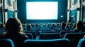 Cinema blank screen and people in blue chairs in the cinema hall. Blurred People silhouettes watching movie performance