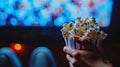cinema with a hand holding popcorn in front of a movie screen, while the blurred cinema hall in the background sets the