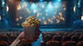 cinema with a hand holding popcorn in front of a movie screen, while the blurred cinema hall in the background sets the