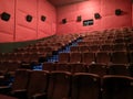 Cinema - interior of a movie theatre with empty red and black seats with white screen Royalty Free Stock Photo