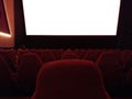 Cinema - interior of a movie theatre with empty red and black seats with white screen - mock-up screen Royalty Free Stock Photo