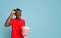 Cinema Offer. Black Guy With Popcorn Looking At Copy Space With Amazement