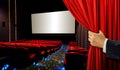 Cinema seats and blank screen with hand opening red curtain Royalty Free Stock Photo