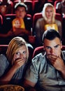 Cinema, shock and couple with popcorn, watching film or eating on romantic date together. Movie night, man and woman in Royalty Free Stock Photo