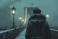 Cinematic back view of cinematic young man in winter coat walking outside in urban city on bridge on a moody, foggy, winters night Royalty Free Stock Photo
