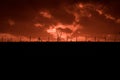 Scary sunset, with red sky and clouds, after storm. Power pylons and industrial fences in devastated landscape. B Evil environment Royalty Free Stock Photo