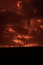 Scary sunset, with red sky and clouds, after storm. Power pylons and industrial fences in devastated landscape. B Evil environment Royalty Free Stock Photo