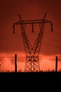 Scary sunset, with red sky and clouds, after storm. Power pylons and industrial fences in devastated landscape. B Evil environment Royalty Free Stock Photo