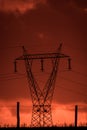 Scary sunset, with red sky and clouds, after storm. Power pylons and industrial fences in devastated landscape. B Evil environment