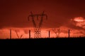 Scary sunset, with red sky and clouds, after storm. Power pylons and industrial fences in devastated landscape. B Evil environment Royalty Free Stock Photo