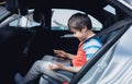 Cinematic portrait Happy young boy using a tablet computer while sitting in the back passenger seat with a safety belt, Child Royalty Free Stock Photo