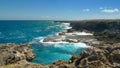 Cinematic shot of emerald colored ocean waves crashing into distant cliffs. Royalty Free Stock Photo