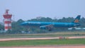 Cinematic shot of a large blue passenger aircraft landing in Hanoi on sunny day.