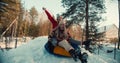 Cinematic slow motion, two beautiful excited happy women sled towards camera on sunny snow forest slope with arms raised