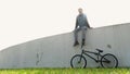 Cinematograph young man with bicycle on green grass sitting in back light