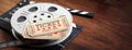 Film reel with retro cinema tickets on top, on a movie clapper, wooden background, copy space, banner, 3d illustration. Royalty Free Stock Photo