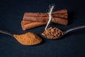 Cinnamon on a black background. A spoonful of young cinnamon lies next to a spoonful of crushed cinnamon.