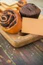 Cinnamon bun and chocolate muffin on a wooden backdrop with empty business card template Royalty Free Stock Photo