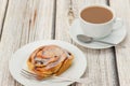 Cinnamon bun on a white plate with a coffee Royalty Free Stock Photo