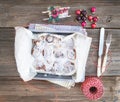 Cinnamon buns with cream-cheese icing in a baking dish with Christmas decorations over a rustic wooden desk Royalty Free Stock Photo