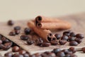 Two cinnamon sticks lie on a beige stand, which is located on the table, on a light background. Coffee beans lie around Royalty Free Stock Photo