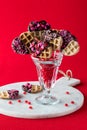 A cinnamon heart filled dessert glass holding decorated Valentine waffle pops.