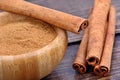 Cinnamon powder in a bowl and sticks on table Royalty Free Stock Photo