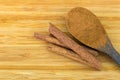 Cinnamon powder on wooden spoon next to Cinnamon sticks made of Royalty Free Stock Photo