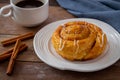 Cinnamon roll bun on white plate and cup of coffee Royalty Free Stock Photo