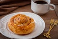Cinnamon roll bun on white plate and cup of coffee Royalty Free Stock Photo