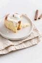 Cinnamon roll or cinnabon with white cream glaze on gray plate on white background. Cinnabons recipe. Traditional homemade sweet