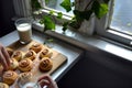cinnamon rolls on wooden board, person with glass milk, ivy on window ledge Royalty Free Stock Photo