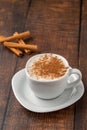 Cinnamon sprinkled salep in a white cup on wooden table Royalty Free Stock Photo
