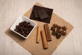 Cinnamon, star anise, coffee beans and dark chocolate on a square hessian cloth,