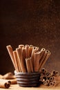 Cinnamon sticks in bowl and powder on brown background. Aromatic spice. Royalty Free Stock Photo