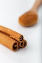 Cinnamon sticks with cinnamon powder in wooden spoon on white background Royalty Free Stock Photo