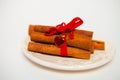 Cinnamon Sticks connected by a red tape on a white background fo Royalty Free Stock Photo