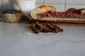 Cinnamon sticks on kitchen table with berry pie on background