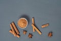 Cinnamon sticks near glass bowl full of powder and scattered stars of anise lies on dark scratched desk on kitchen. Space for text Royalty Free Stock Photo