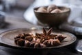 Cinnamon sticks, nutmeg and anise stars in cups over dark scorched wooden background