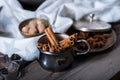 Cinnamon sticks, nutmeg and anise stars in cups over dark scorched wooden background