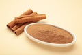 Cinnamon sticks and powder in bowl on beige background Royalty Free Stock Photo