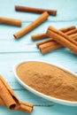 Cinnamon sticks and powder in bowl on blue background. Vertical photo Royalty Free Stock Photo